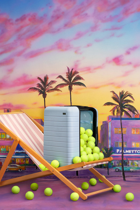 Serena Williams Away Suitcase on beach chair with tennis balls and purple background Serena Williams Away luggage on beach chair with tennis balls