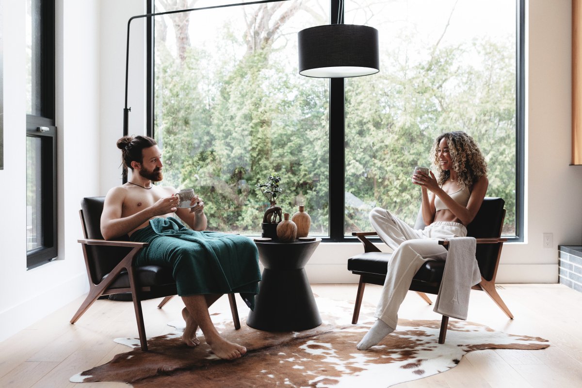 A man and a woman sitting in their living room, both sporting Aestate premium towels