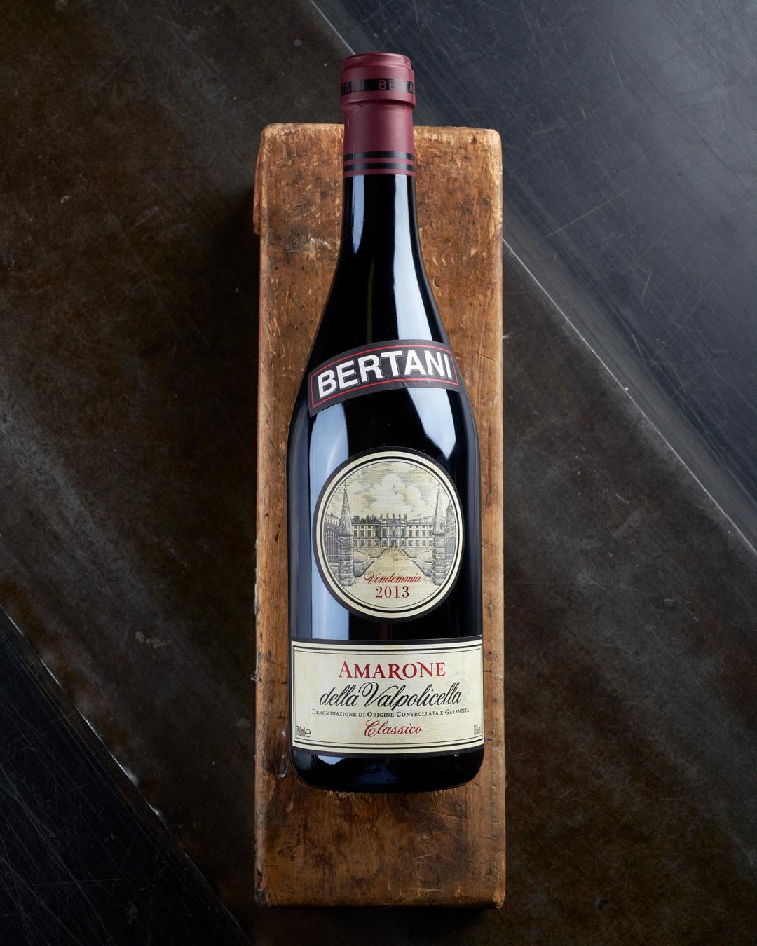 Bottle of red Bertani wine on a wooden block.