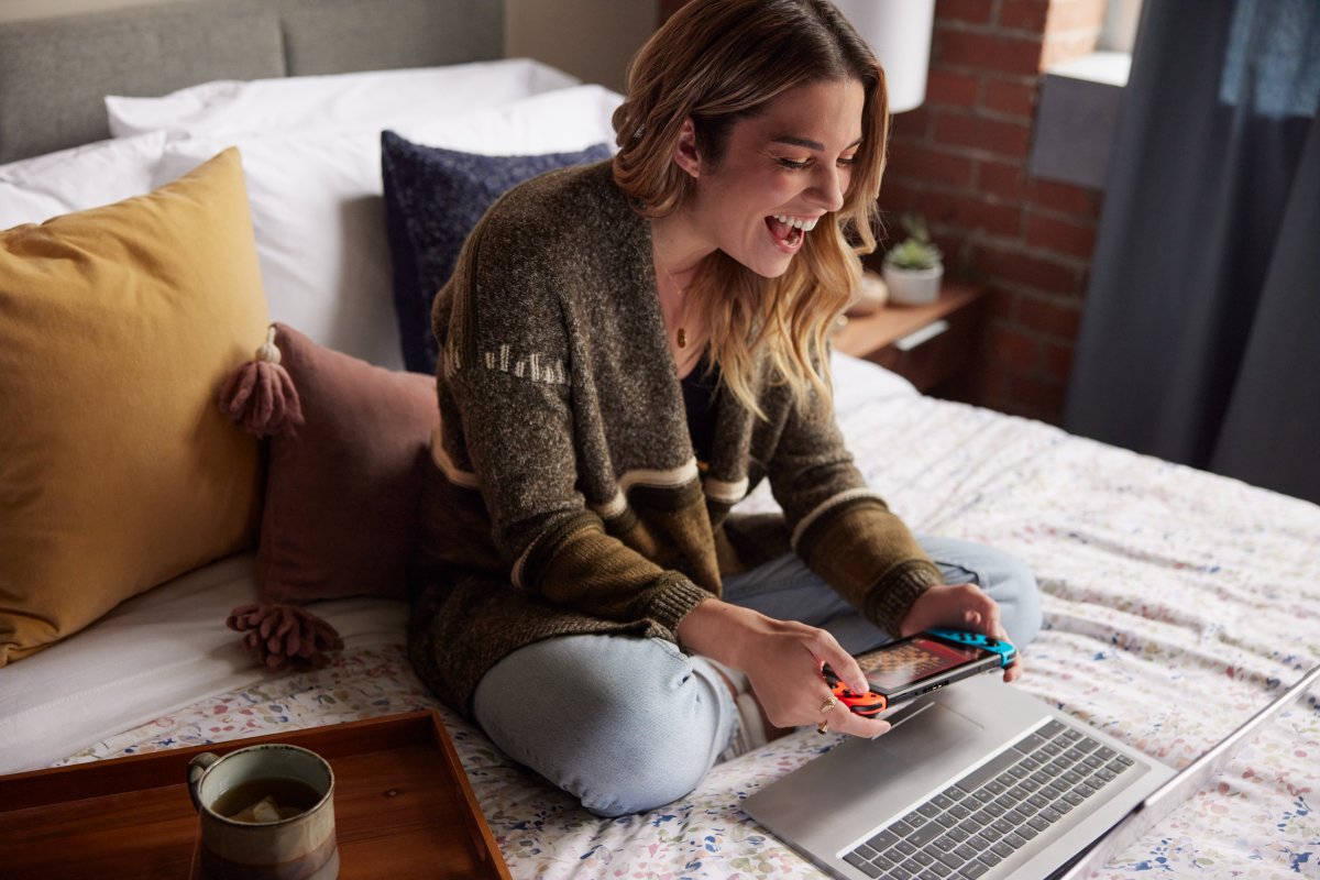 Annie Murphy sitting on a bed, playing with her Nintendo Switch