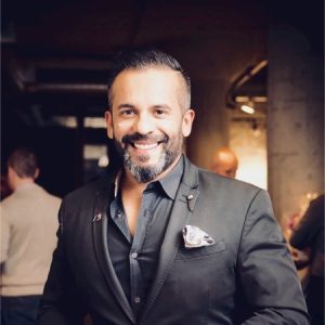 A man in a suit smiles at the camera, he is Curtis Khan, CEO of BookJane.
