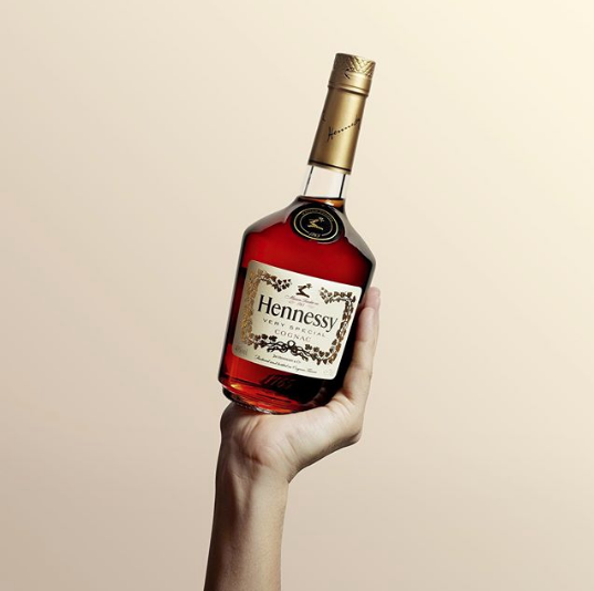 Hand holding up bottle of hennessy