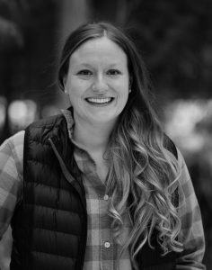 Black and white photo of a woman smiling at the camera. it is Jackie Rhind, founder of OVRY.