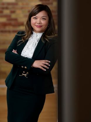 Jane Wang in black suit and white shirt leaning against a wall